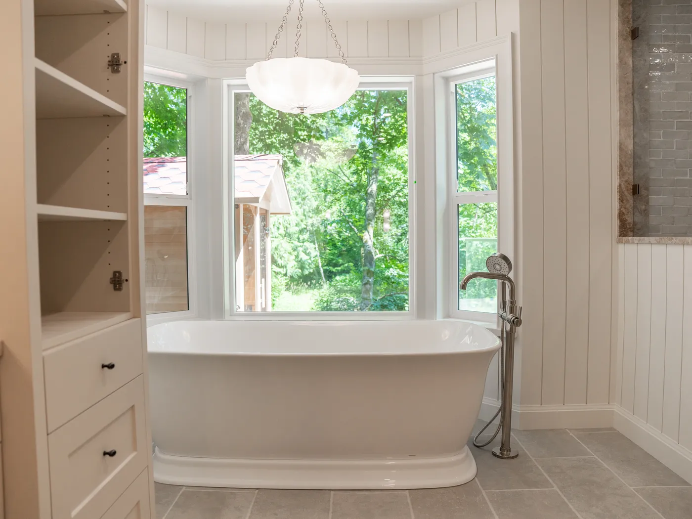 Ensuite with freestanding tub in a bay window and built-in storage