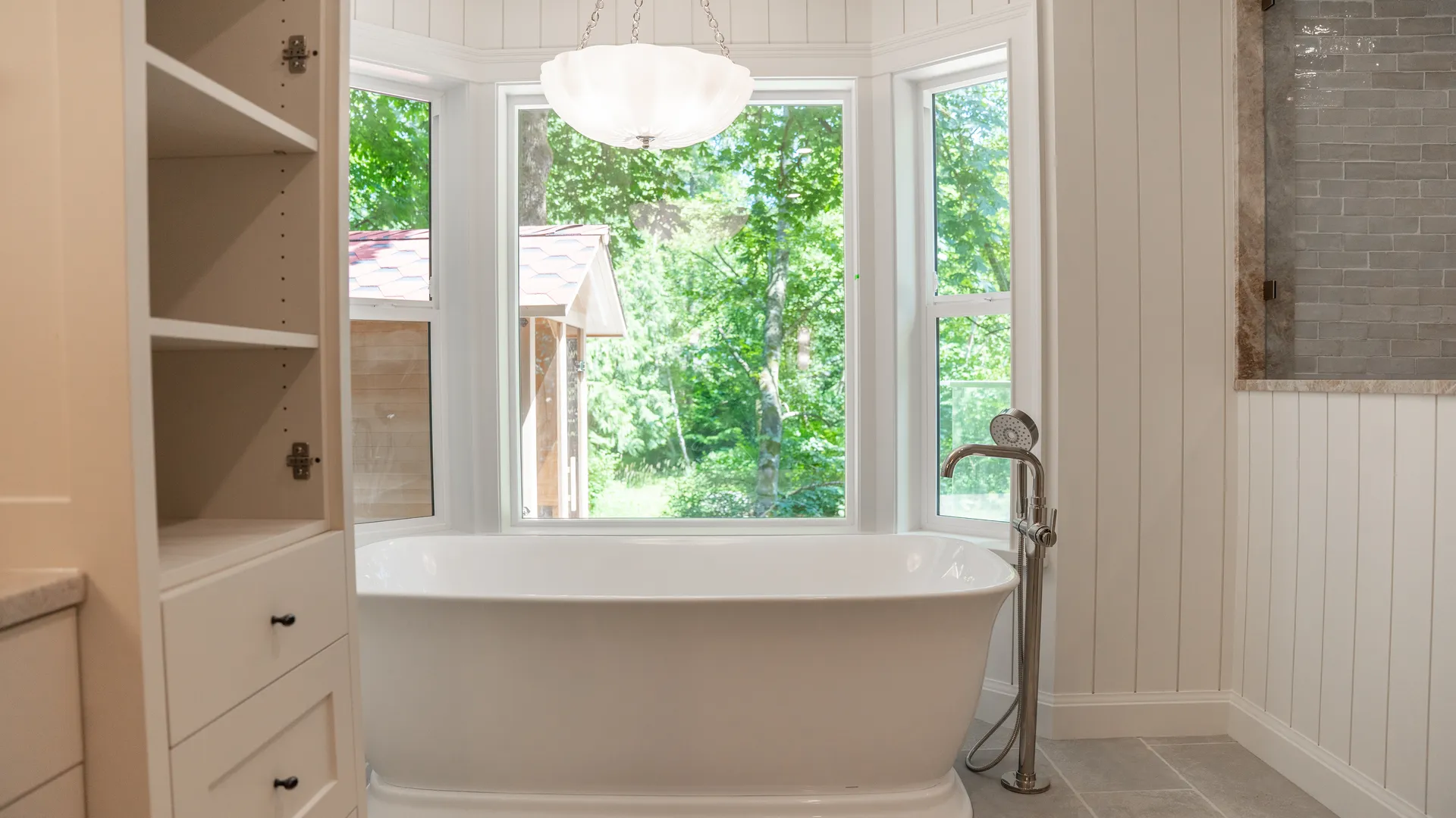 Ensuite with freestanding tub in a bay window and built-in storage