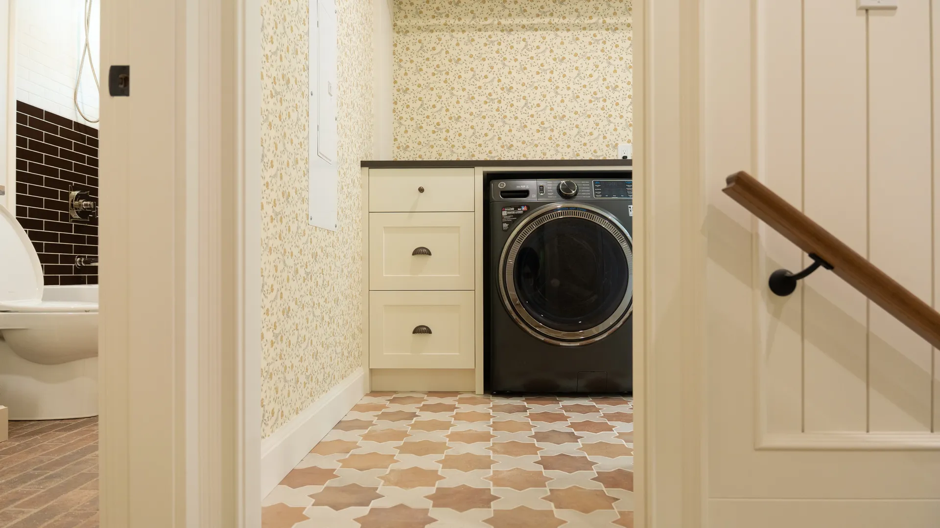 Laundry room with patterned tile floor and custom cabinetry